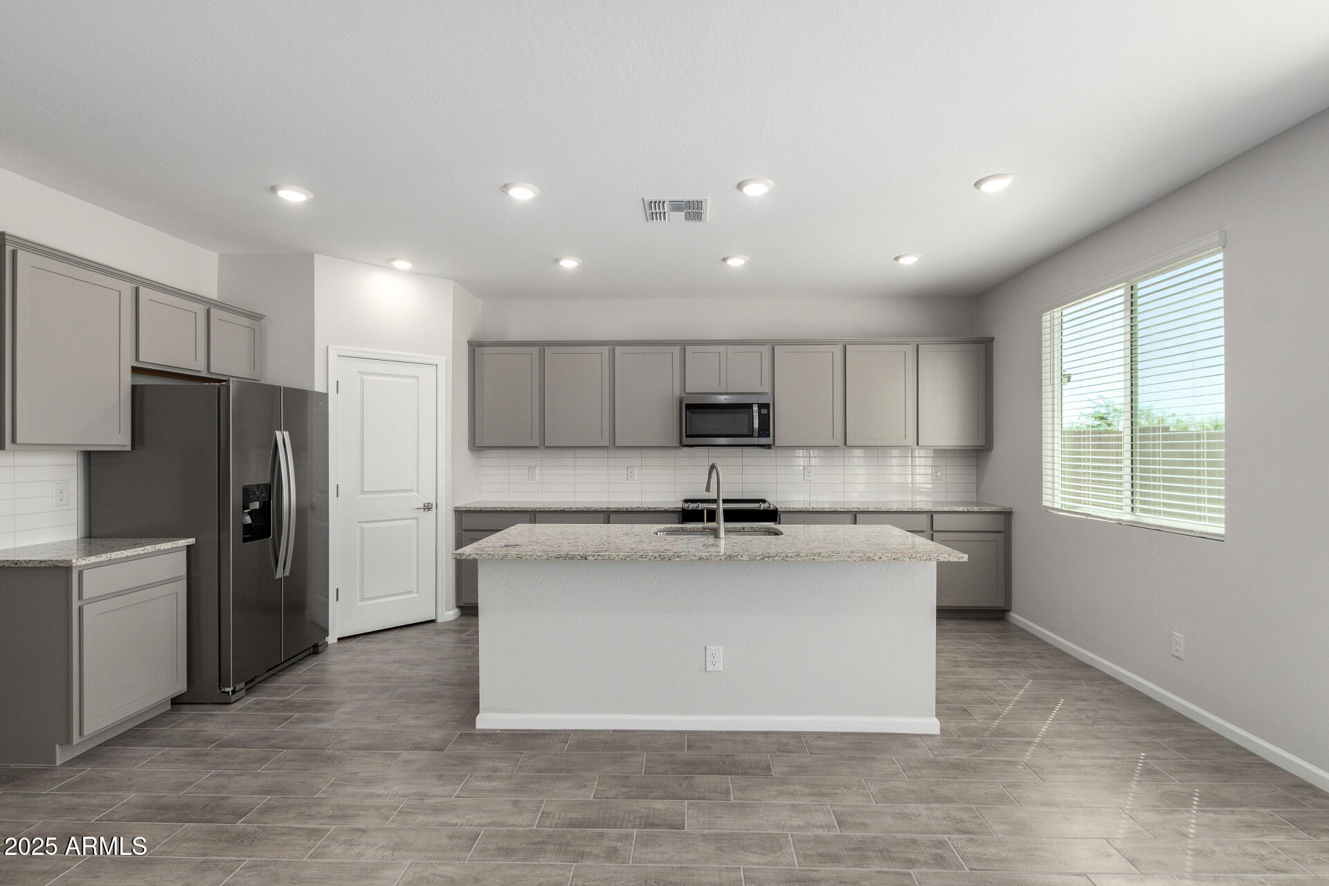 18207 West Daley Lane Surprise, AZ 85387 - Photo 12 of 40 a large kitchen with stainless steel appliances kitchen island a large counter top and a refrigerator