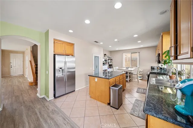 a kitchen with stainless steel appliances kitchen island granite countertop dining table chairs and a refrigerator