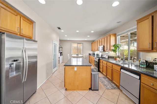 a kitchen with stainless steel appliances granite countertop a refrigerator a sink a stove and island