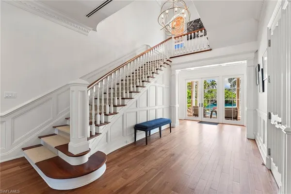 a dining room with wooden floor a chandelier a wooden table and chairs