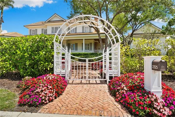 a front view of a house with a yard and fountain in middle of the road