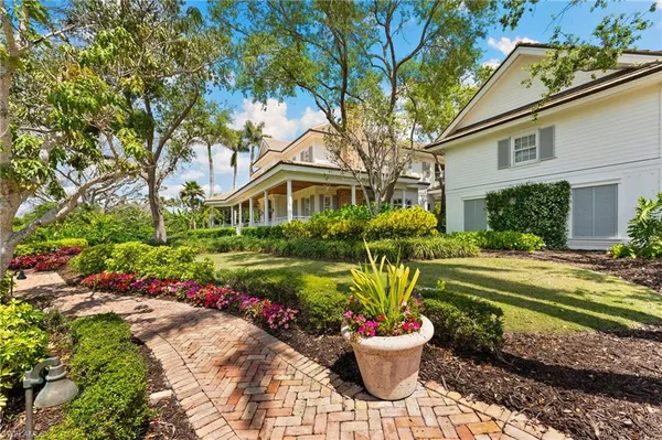 a view of a white house with a yard and potted plants