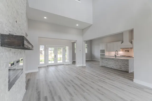 an empty room with wooden floor fireplace and windows