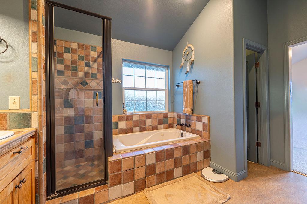 10132 Ranch Road Rough and Ready, CA 95975 - Photo 25 of 54 a spacious bathroom with a tub a sink and a large mirror next to a window