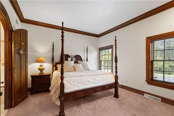 a bedroom with a bed a dresser and windows