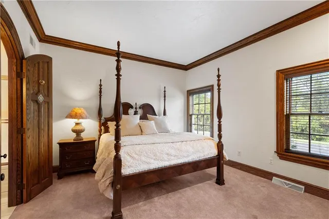 a bedroom with a bed a dresser and windows