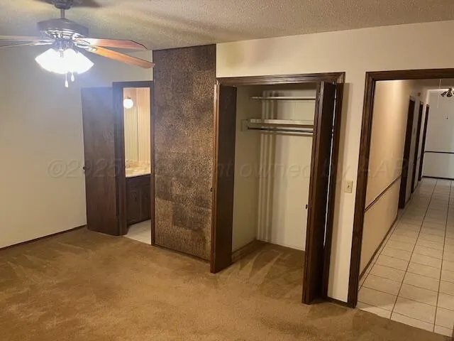 an empty room with closet and a chandelier fan