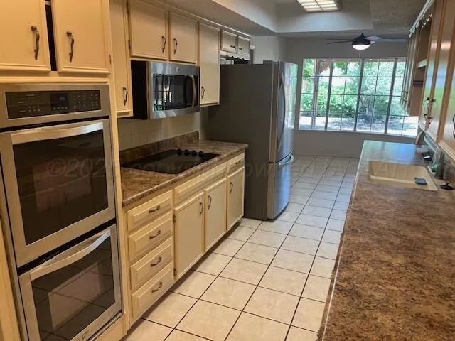 a kitchen with granite countertop a stove a microwave a refrigerator a sink dishwasher and cabinets