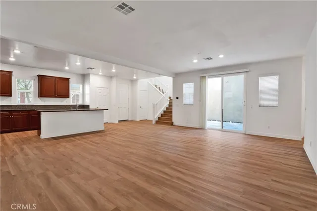 a view of a big room with wooden floor and a kitchen