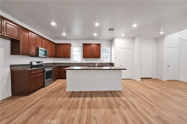 a large kitchen with stainless steel appliances granite countertop a stove a sink dishwasher and a microwave oven on the wooden floor