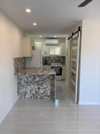 a kitchen with kitchen island granite countertop a refrigerator and a counter top space