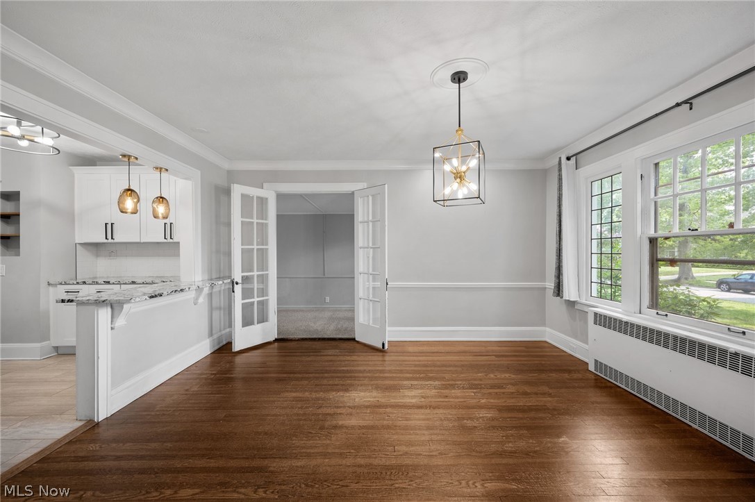 2924 Brighton Road Shaker Heights, OH 44120 - Photo 9 of 31 Unfurnished dining area featuring radiator heating unit, french doors, hardwood / wood-style flooring, a chandelier, and baseboards