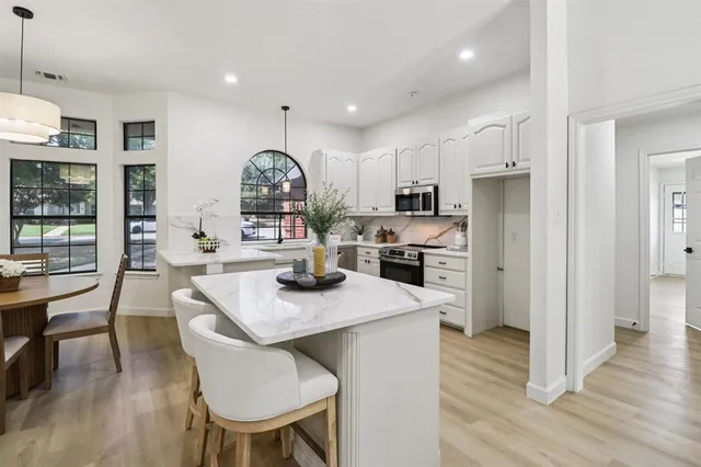 a kitchen with stainless steel appliances granite countertop a table chairs refrigerator and microwave