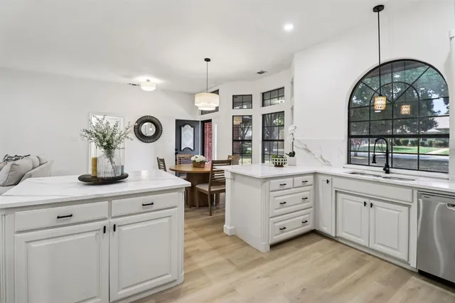 a kitchen with kitchen island a dining table chairs and white cabinets