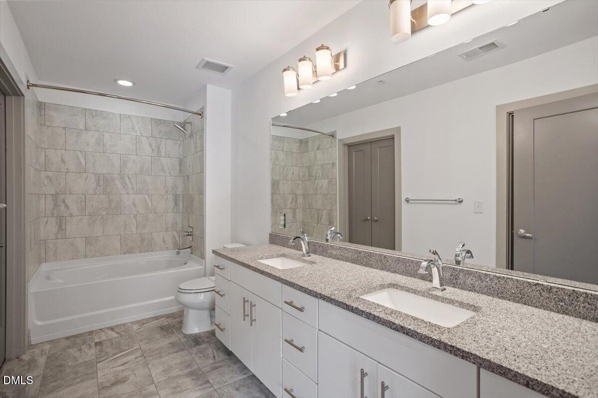 1300 St Marys Street, Unit 207 Raleigh, NC 27605 - Photo 12 of 31 a bathroom with a granite countertop bathtub shower sink vanity and toilet