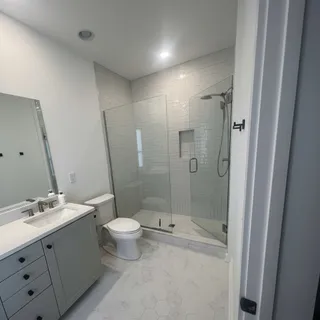 a bathroom with a shower sink vanity mirror and toilet