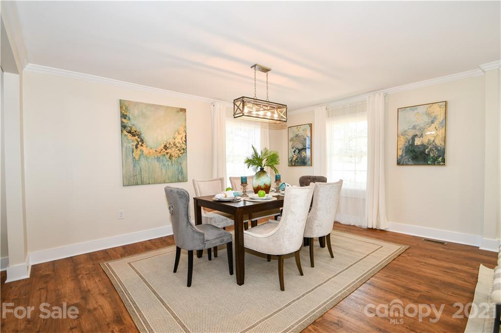 1119 West Sandy Ridge Road Monroe, NC 28112 - Photo 8 of 22 a dining room with wooden floor a chandelier a wooden table and chairs