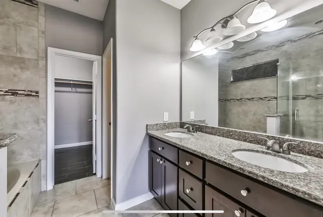 a bathroom with a granite countertop sink a large mirror and a shower