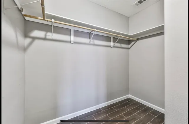 an empty room with wooden floor chandelier fan and windows