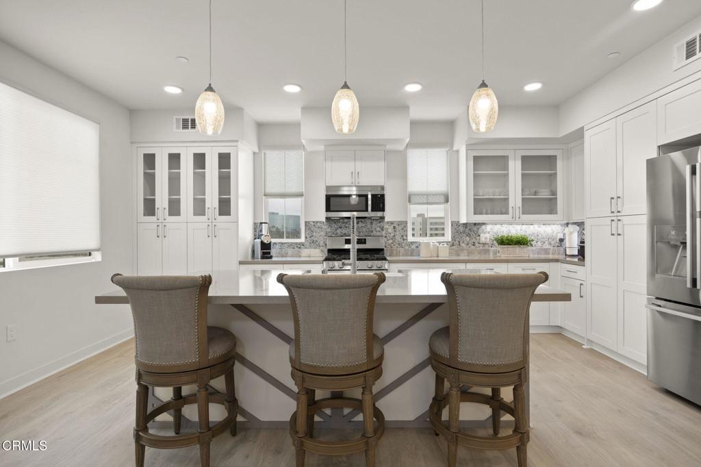 a view of a dining room with furniture a kitchen and chandelier