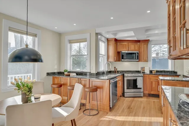 a kitchen with stainless steel appliances granite countertop a stove a sink a microwave a dining table and chairs