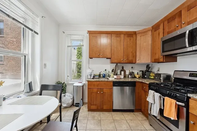 a kitchen with stainless steel appliances a stove a sink dishwasher and white cabinets with wooden floor