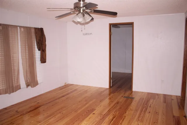 an empty room with wooden floor closet and windows