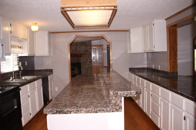 a kitchen with granite countertop a sink a stove and cabinets