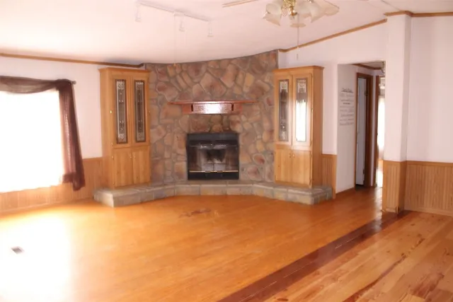 a view of empty room with wooden floor and fireplace