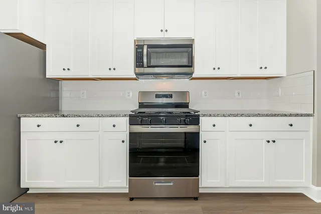 a kitchen with granite countertop white cabinets and stainless steel appliances