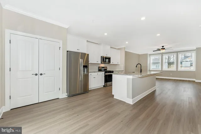 a large kitchen with a center island wooden floor stainless steel appliances and windows