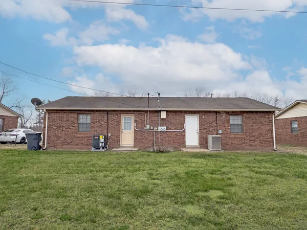 a view of a brick house with a big yard and large tree