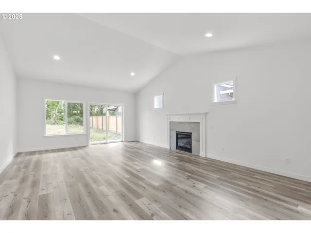 a view of empty room with wooden floor and fireplace