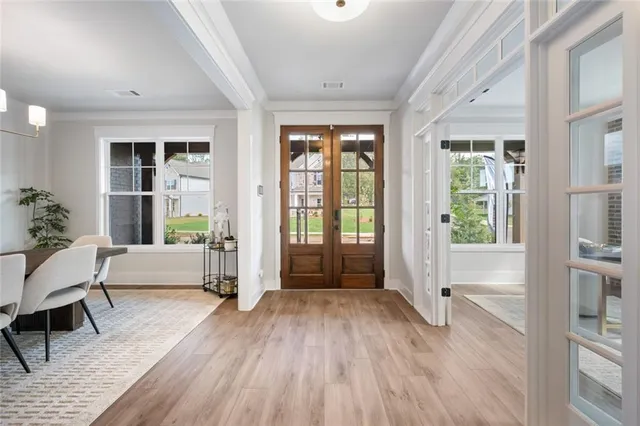 a kitchen with stainless steel appliances granite countertop a refrigerator a sink dishwasher a stove and a dining table with wooden floor