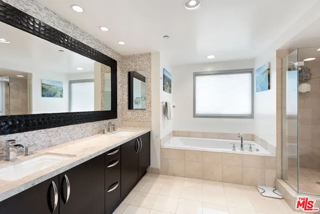 a bathroom with a tub a sink double vanity and a mirror