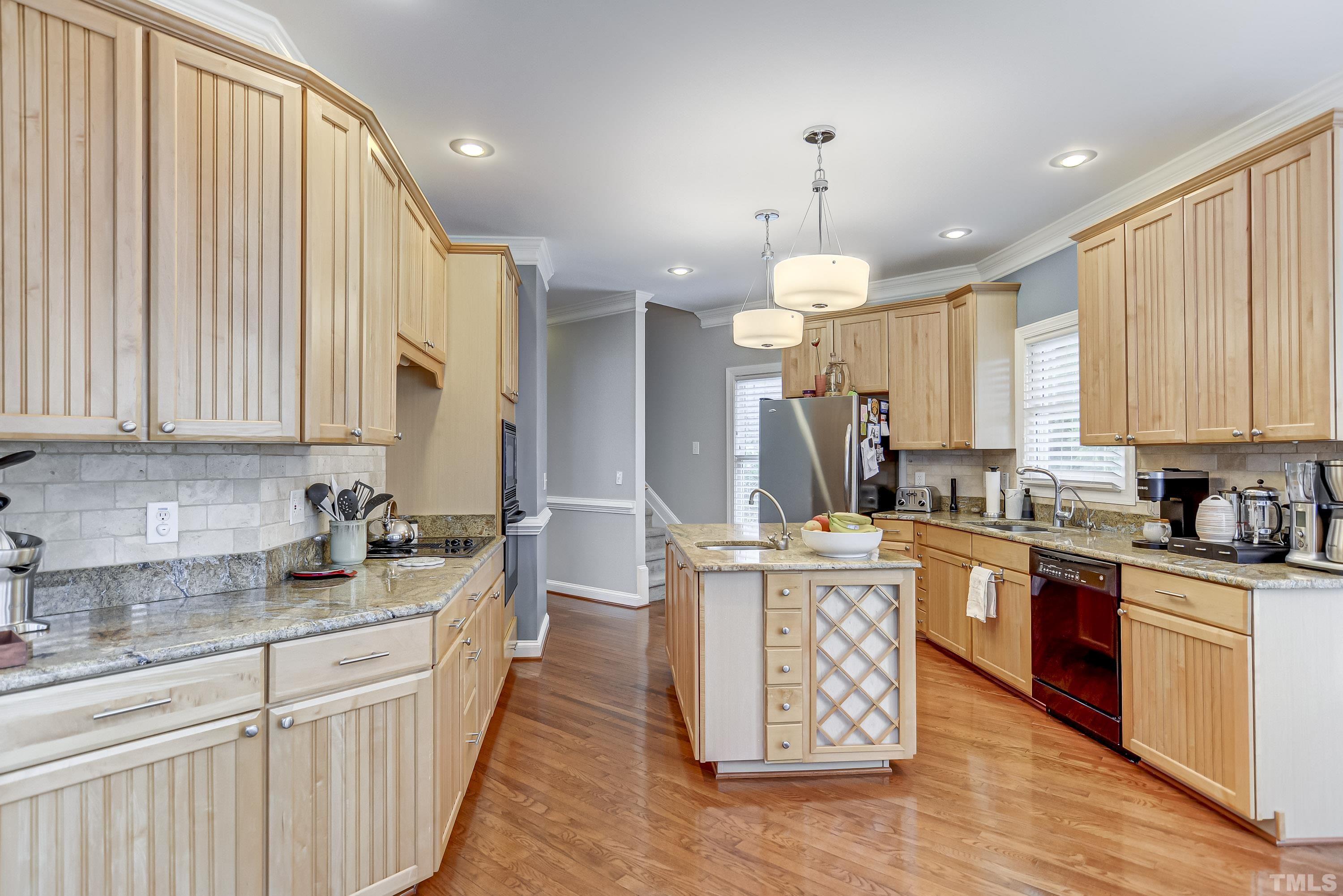 1005 Fieldgrass Place Raleigh, NC 27603 - Photo 8 of 27 a kitchen with stainless steel appliances kitchen island granite countertop a stove a sink dishwasher and a refrigerator with wooden floor