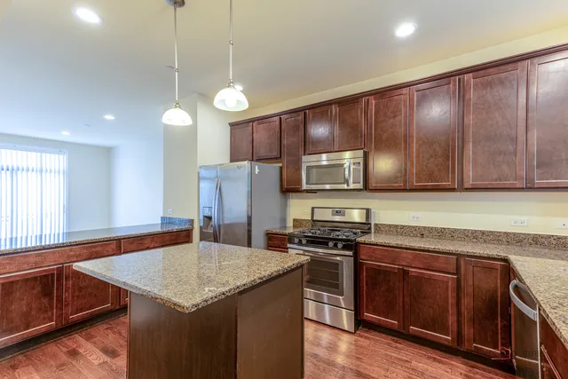 a kitchen with stainless steel appliances granite countertop a sink a stove and a refrigerator