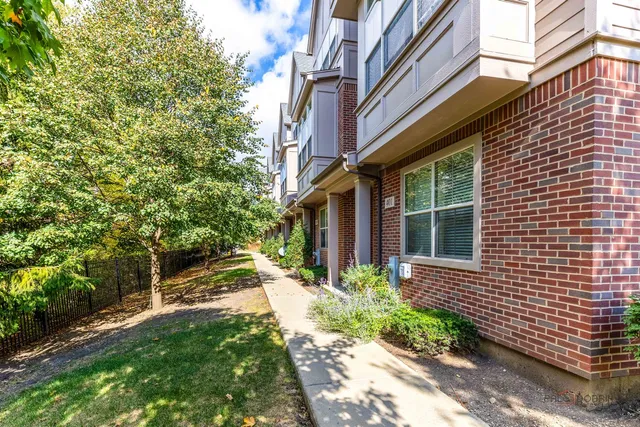 a view of brick house with a yard and potted plants