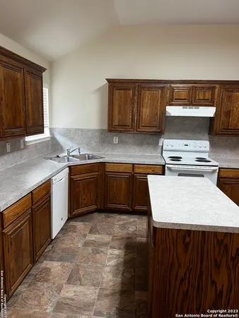 a kitchen with kitchen island granite countertop wooden cabinets and white appliances