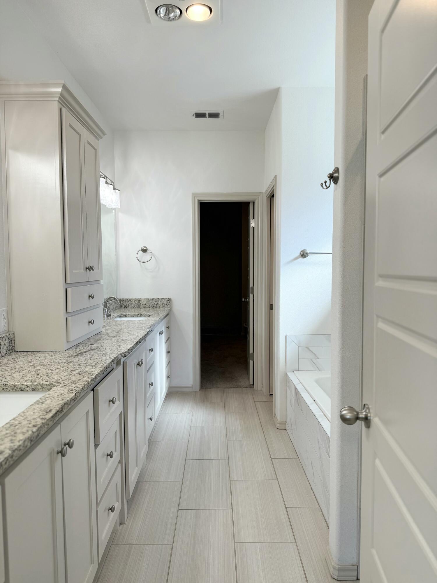12202 Ithaca Avenue Lubbock, TX 79423 - Photo 12 of 28 a spacious bathroom with a granite countertop sink and a mirror