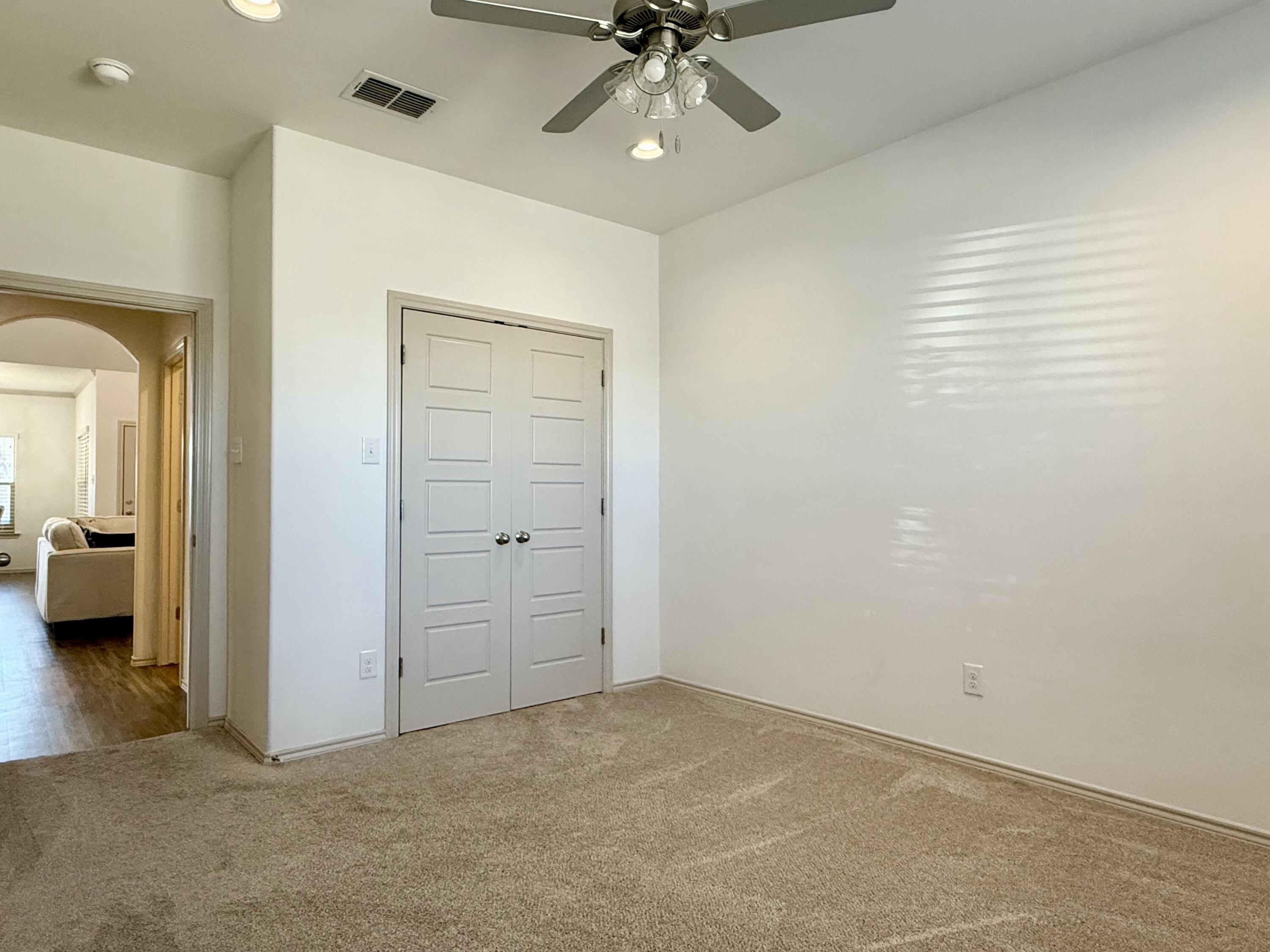 12202 Ithaca Avenue Lubbock, TX 79423 - Photo 17 of 28 an empty room with a mirror and a ceiling fan