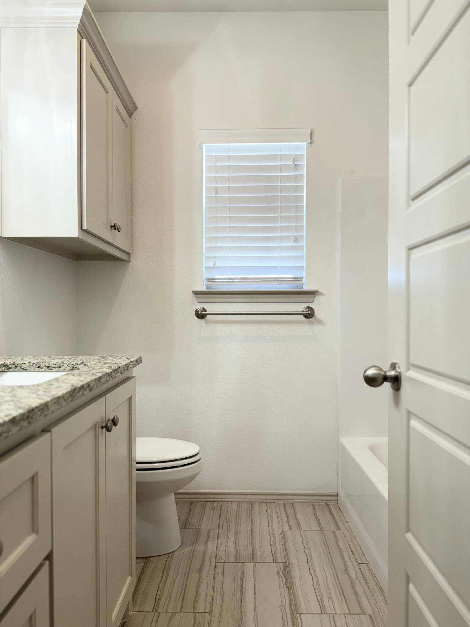12202 Ithaca Avenue Lubbock, TX 79423 - Photo 19 of 28 a bathroom with a granite countertop sink toilet and a vanity