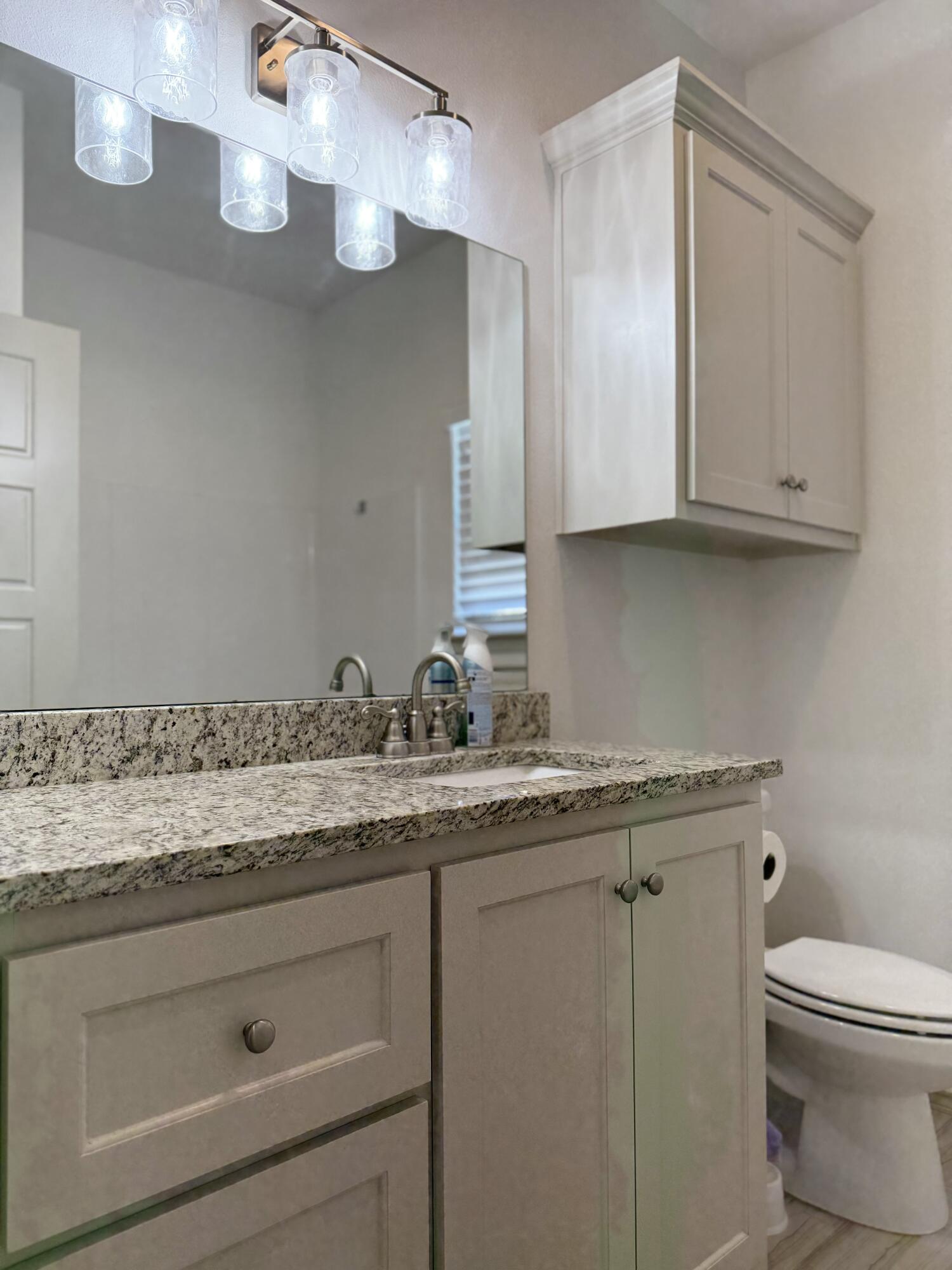 12202 Ithaca Avenue Lubbock, TX 79423 - Photo 20 of 28 a bathroom with a granite countertop sink a toilet and mirror