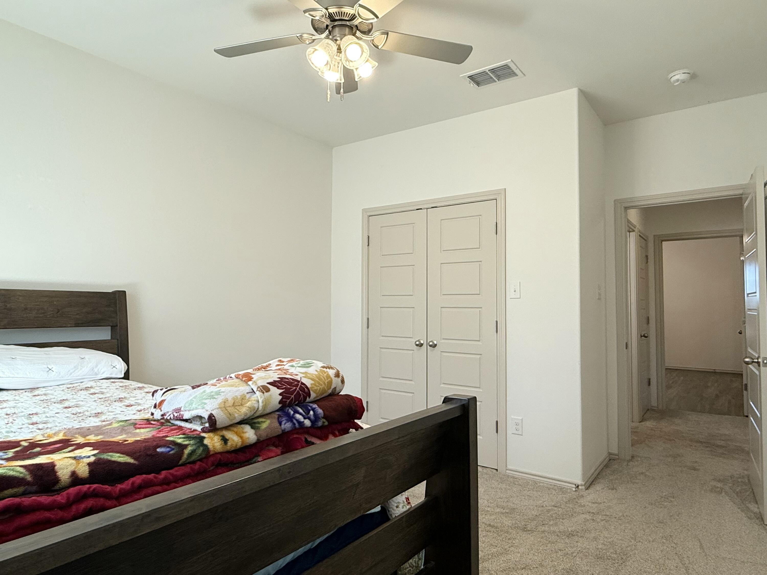 12202 Ithaca Avenue Lubbock, TX 79423 - Photo 22 of 28 a bedroom with a bed and a chandelier