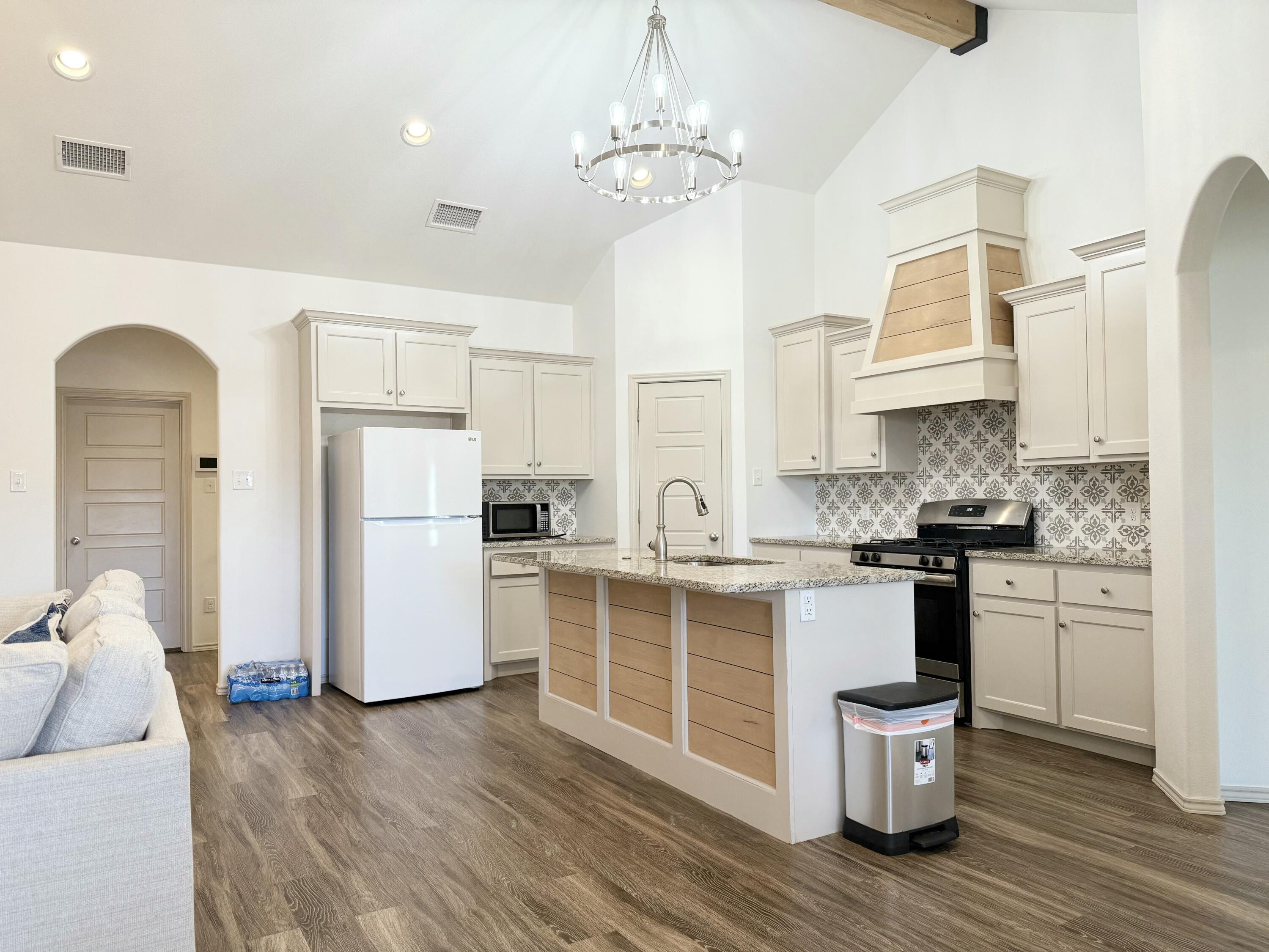 12202 Ithaca Avenue Lubbock, TX 79423 - Photo 6 of 28 a kitchen with stainless steel appliances granite countertop a refrigerator a sink dishwasher a stove and white cabinets with wooden floor