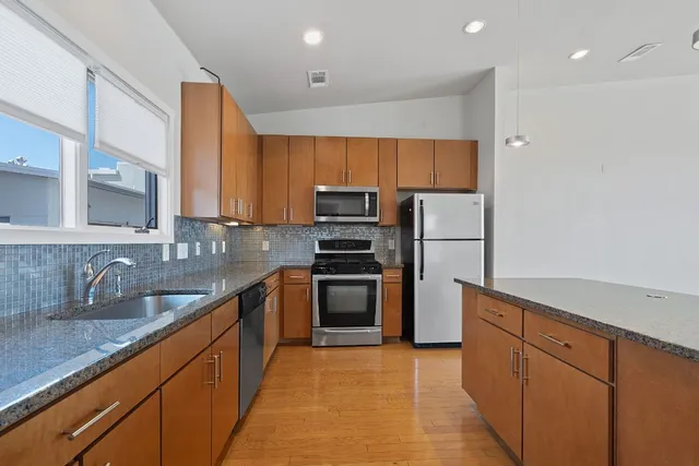 a kitchen with stainless steel appliances granite countertop a refrigerator and a sink