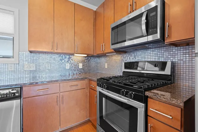 a kitchen with granite countertop cabinets stainless steel appliances and wooden cabinets