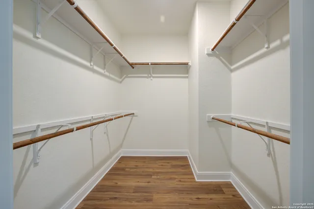 an empty room with wooden floor chandelier fan and closet area