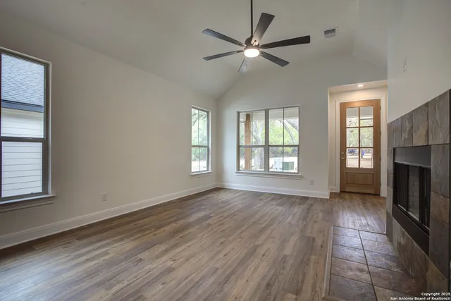an empty room with wooden floor fan and windows