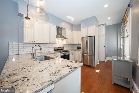 a kitchen with granite countertop a stove and a wooden floors